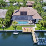 Aerial waterfront house with screened pool, dock