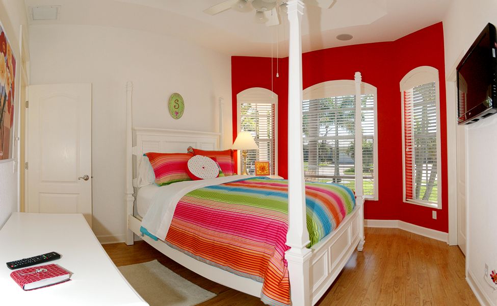A bedroom with a bed, ceiling fan and red walls.
