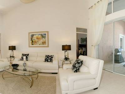 A living room with white furniture and a glass table.