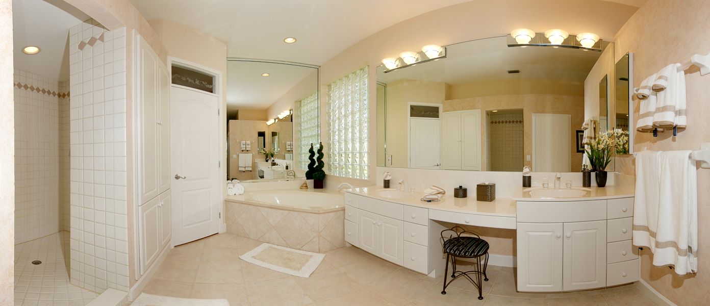 A bathroom with a tub, sink and mirror.