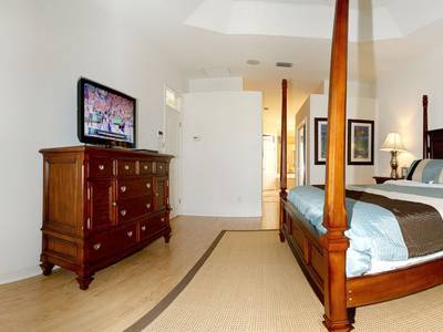 A bedroom with a bed, dresser and television.