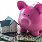 A pink piggy bank sitting on top of some money.