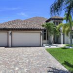 A large driveway with two garage doors and palm trees.