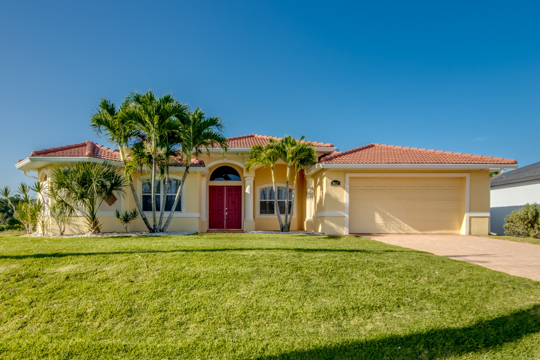 Yellow house with red door and palms