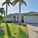 A large white house with palm trees in the front yard.