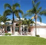Pink stucco home with palms and manicured lawn