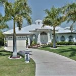 A white house with palm trees in front of it.