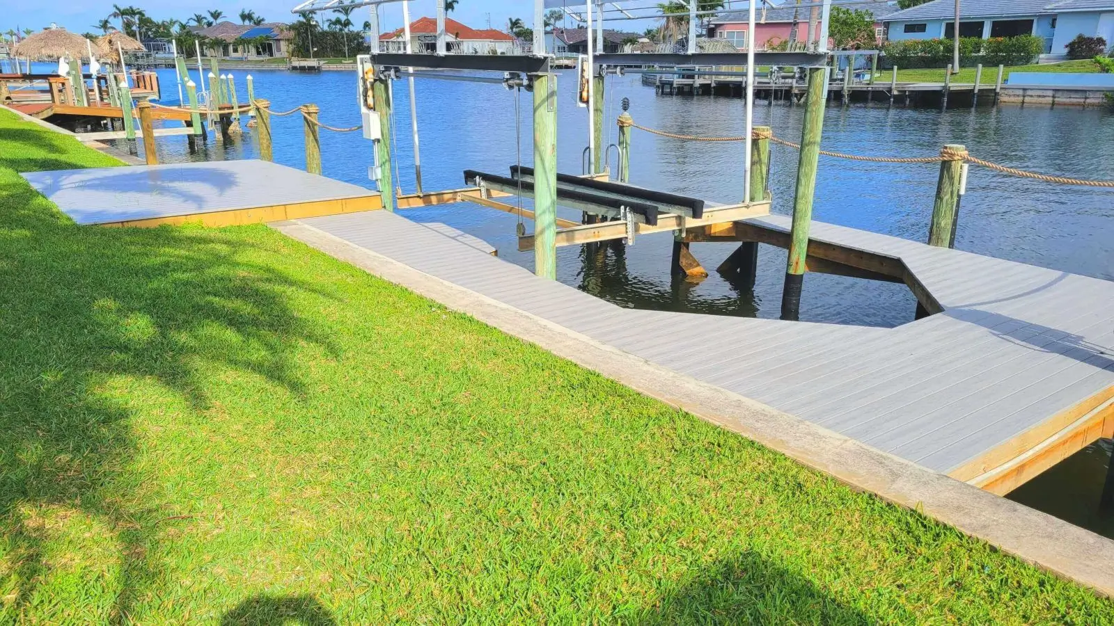 A dock with grass and water in the background.